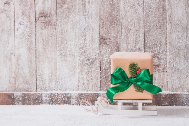 Free photo gift brown with green bow on sled