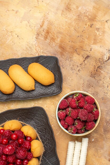 A gift cake and biscuits on brown plates fruits on mixed color table vertical view