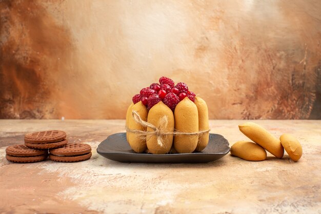 A gift cake and biscuits on brown plates fruits on mixed color table 