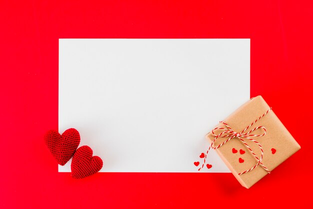 Gift and knitted hearts on paper sheet