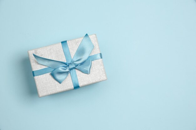 ギフト、プレゼントボックス。背景に青色のモノクロのスタイリッシュでトレンディな構成。上面図、フラットレイ。周りのいつものものの純粋な美しさ。広告のコピースペース。休日、お祝い。
