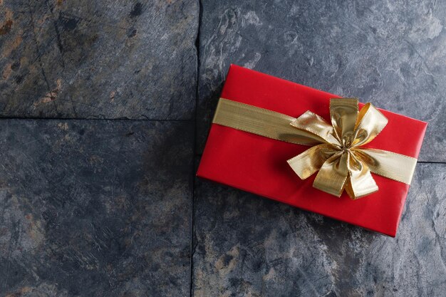 Giftbox with golden ribbon on grey stone background