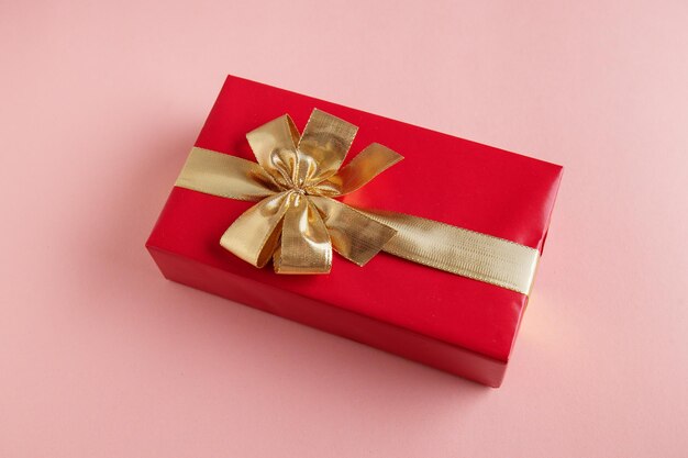 Подарочная коробка с золотой лентой на розовом фоне