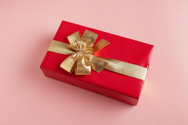 Giftbox with golden ribbon on pink background