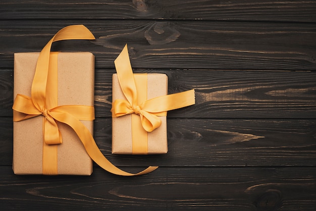 Free photo gifts tied with golden ribbon on wooden background and copy space