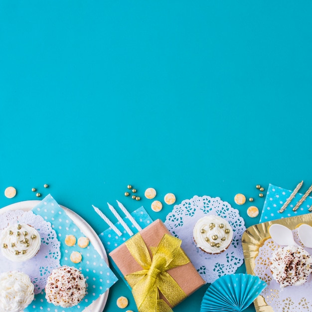 Gifts with muffins on plate and tray at the edge of blue background