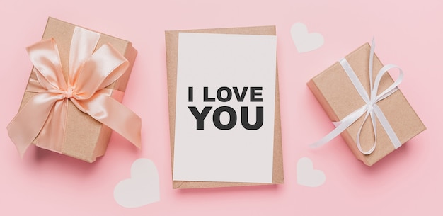 Подарки с запиской на изолированном розовом фоне, концепция любви и валентинки с текстом, я люблю тебя
