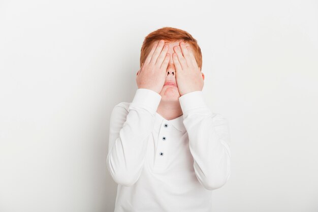 Ginger boy covering his eyes