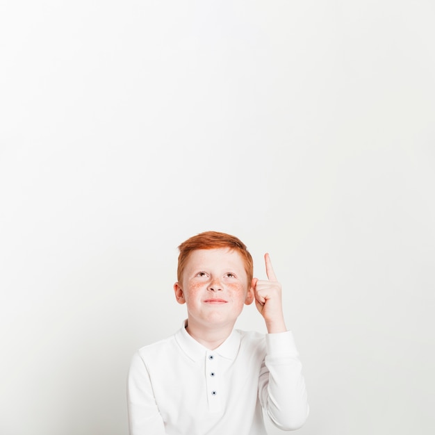 Free photo ginger boy pointing up towards copyspace