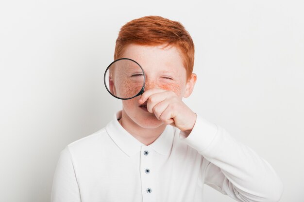 Free photo ginger boy with magnifying glass