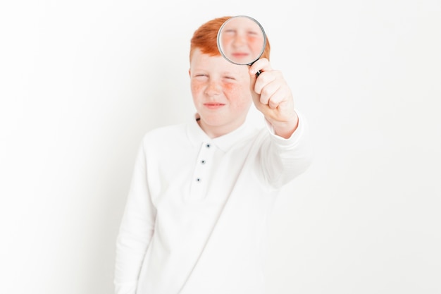 Free photo ginger boy with magnifying glass