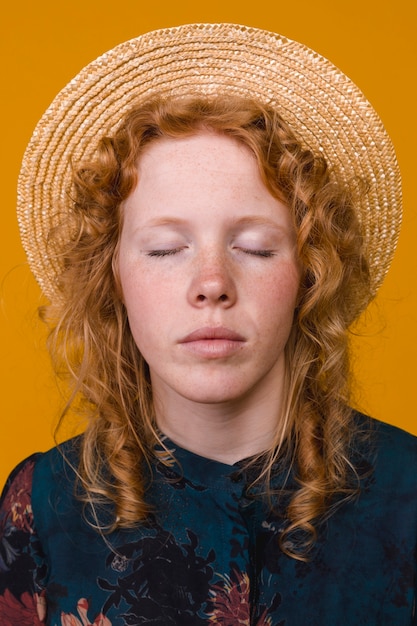 Ginger freckled woman in hat with closed eyes