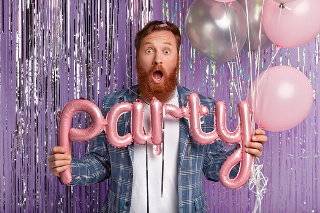 Ginger man at party holding balloons