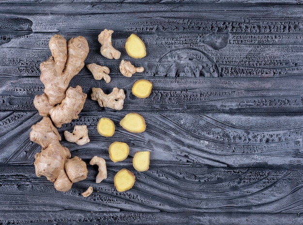 Ginger with ginger slices flat lay on a dark wooden background space for text