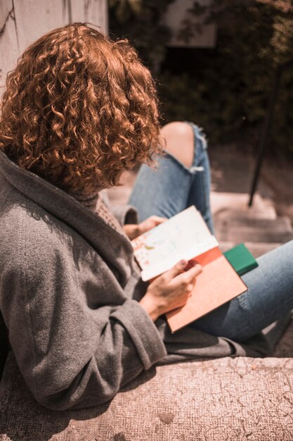 Ginger woman holding book on stair