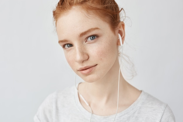 Ginger woman listening music in headphones.