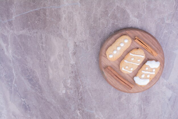 Free photo gingerbread christmas cookies with cinnamon sticks on round wooden board.