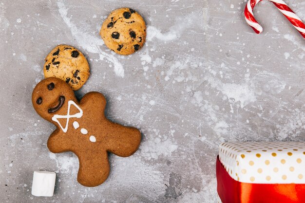 Gingerbread, cookies, marshmallows, red white cnadies lie on the floor around present box