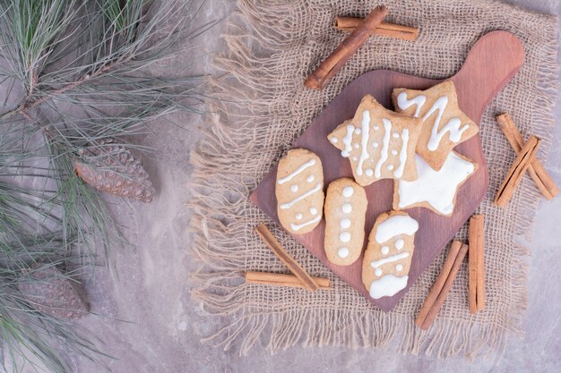 Gingerbread cookies in star and ovale shapes with cinnamon sticks on wooden platter.