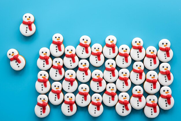 Free photo gingerbread snowmen covered with icing on a blue background flat lay