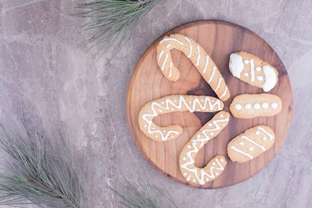 Gingerbread stick cookies with oval ones on wooden board.