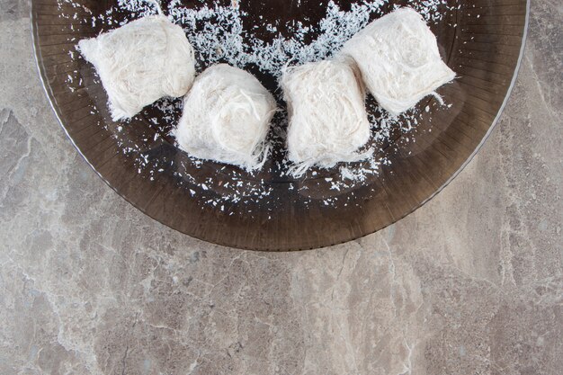 Gingerbread with jam in sugar glaze and cotton candies on a plate , on the marble.