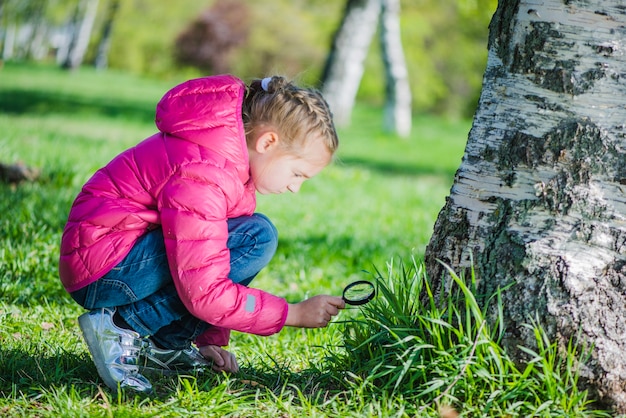 Girl analyzing the lawn with a magnifying glass