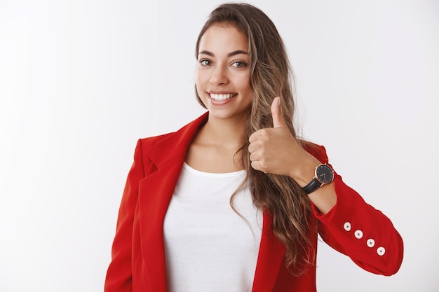 Girl assuring you have lucky day. Happy smiling gorgeous female entrepreneur showing thumb up, liking approving awesome idea delighted giving positive reply, agree, standing white wall