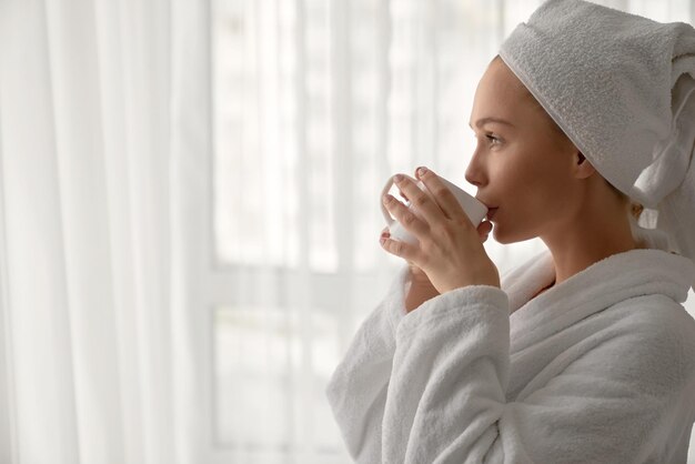 Girl in bathrobe drinking cup of coffee
