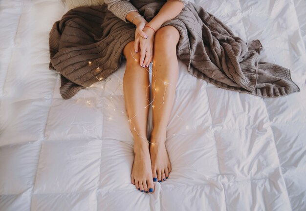 베이지 색 베일과 갈 랜드의 불빛에 아름다운 다리와 침대에 여자