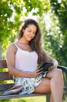 Free photo girl on bench in park with ereader