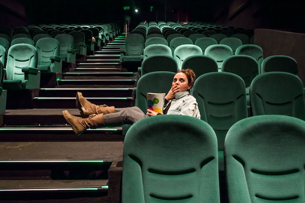 Foto gratuita ragazza nella grande sala cinematografica con popcorn