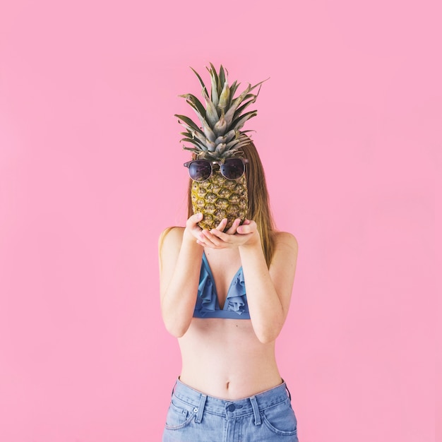 Girl in bikini with pineapple in front of face