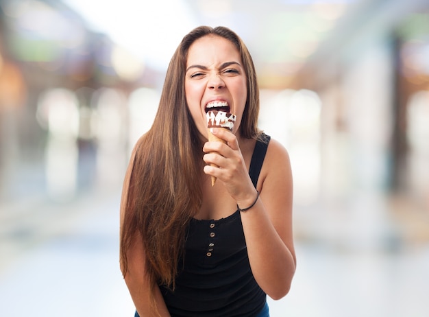 Girl biting ice cream with expression.