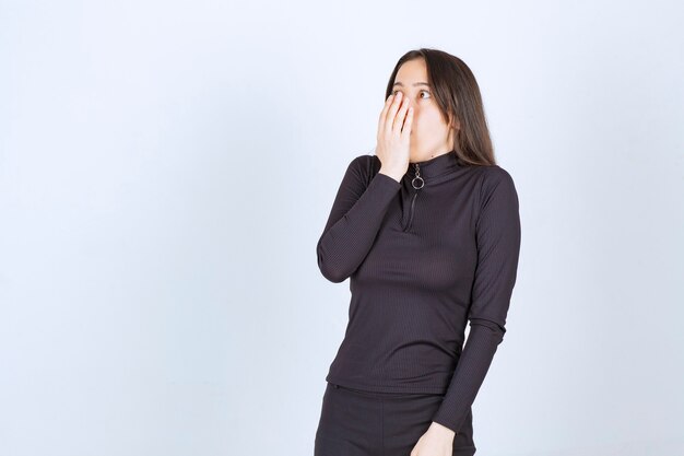 Girl in black clothes looking surprised and scared. 
