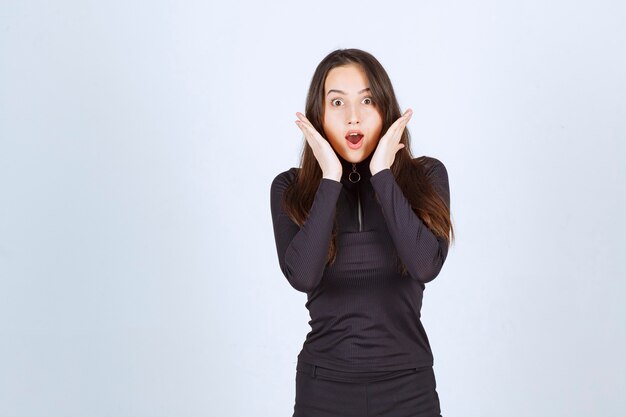 Girl in black clothes looking surprised and scared. 