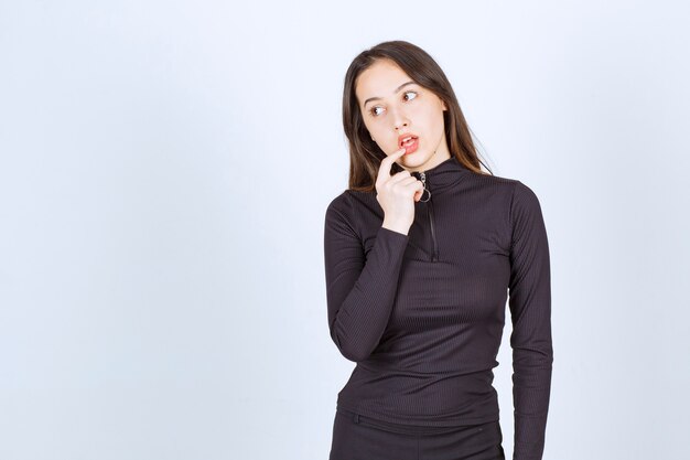 Girl in black clothes looks thoughtful and doubtful. 