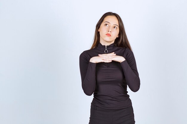 Girl in black clothes looks thoughtful and doubtful. 