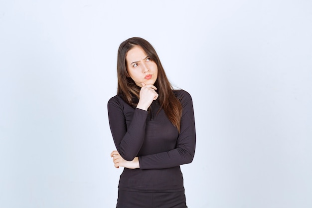 Girl in black clothes looks thoughtful and doubtful. 