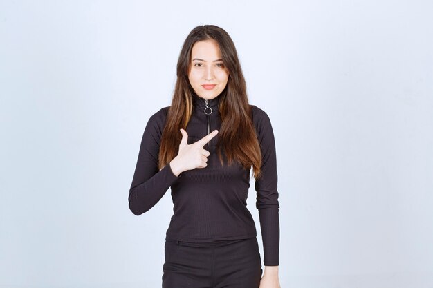 Girl in black clothes pointing at something up. 