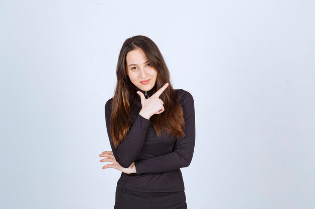 Girl in black clothes pointing at something up. 