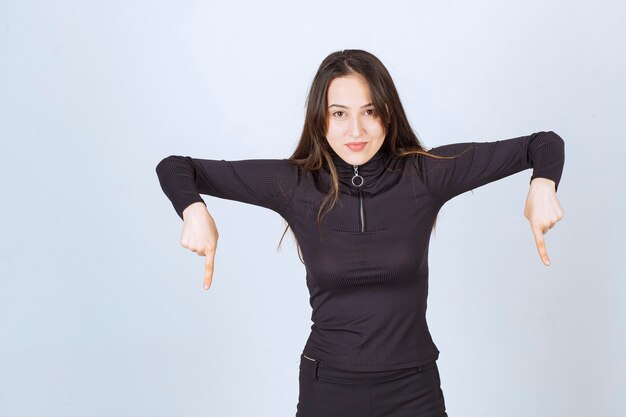 Girl in black clothes pointing below. 