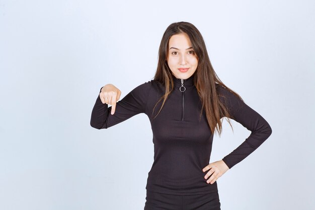 Girl in black clothes pointing below. 