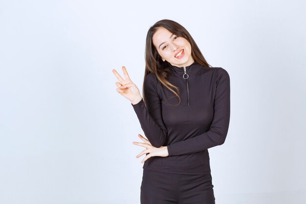 Girl in black clothes showing peace and friendship sign. 