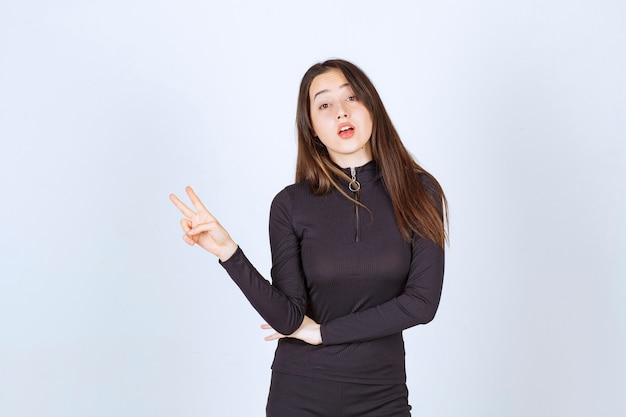 Free photo girl in black clothes showing peace and friendship sign.