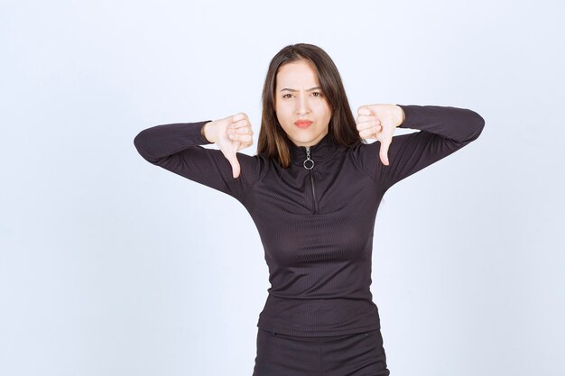 Girl in black clothes showing thumb down sign. 