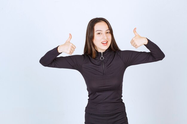 Girl in black clothes showing thumb up sign. 