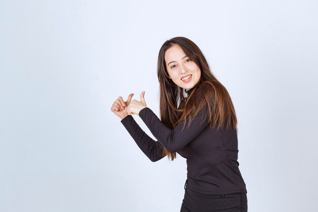 Girl in black clothes showing thumb up sign. 