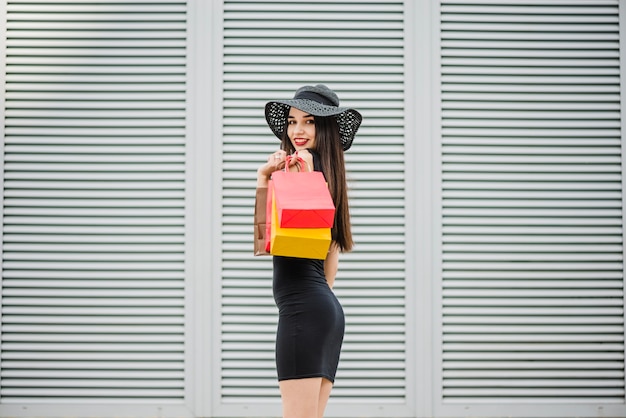 Free photo girl in black dress carrying shopping bags