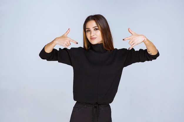 Foto gratuita ragazza in camicia nera che indica se stessa. foto di alta qualità